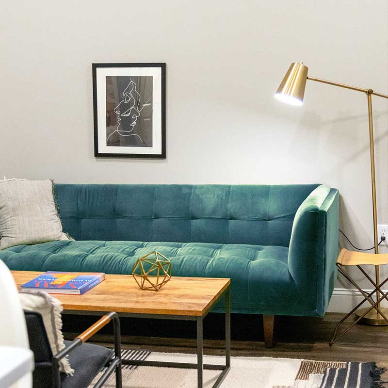 A cozy lounge area with a teal sofa, wooden coffee table, and gold lamp.